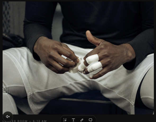 Close-up of a player wrapping tape around his fingers in a locker room