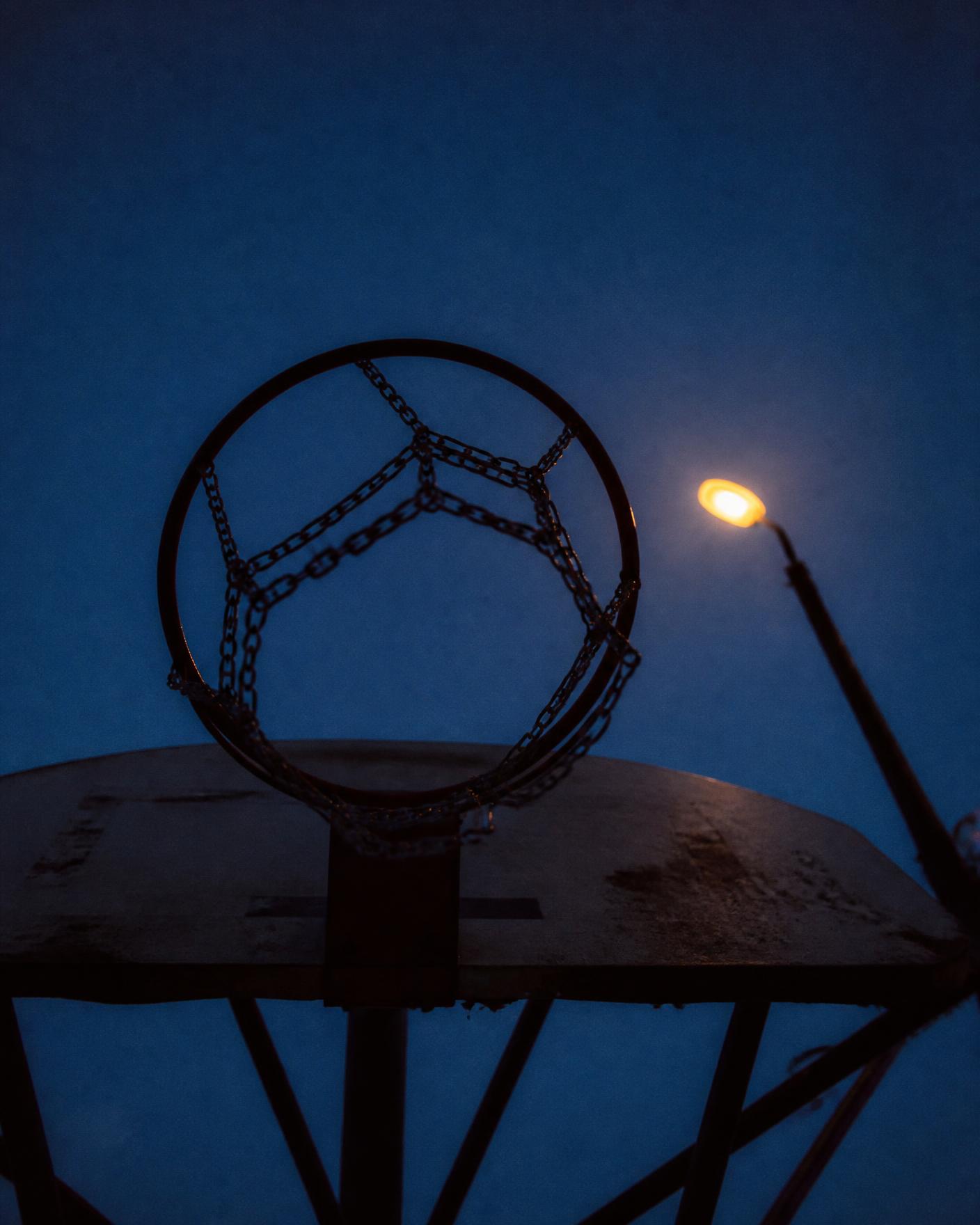 Looking up through a chain net hoop at a streetlight at dusk